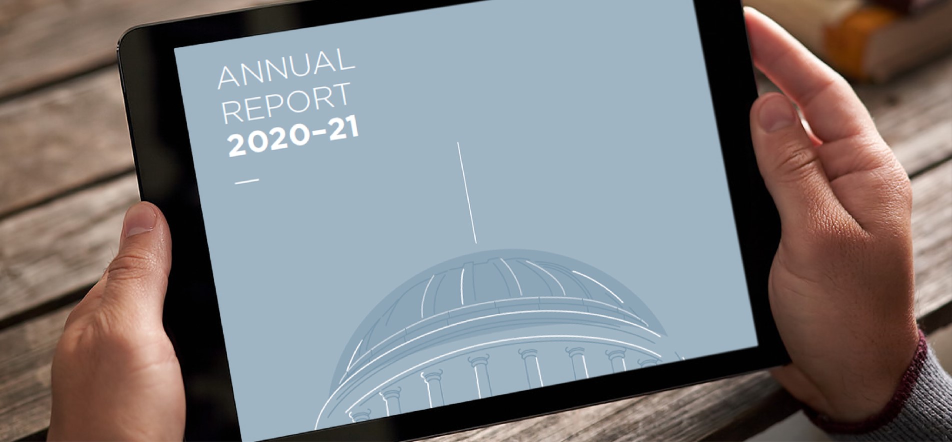 Hands holding tablet displaying annual report cover